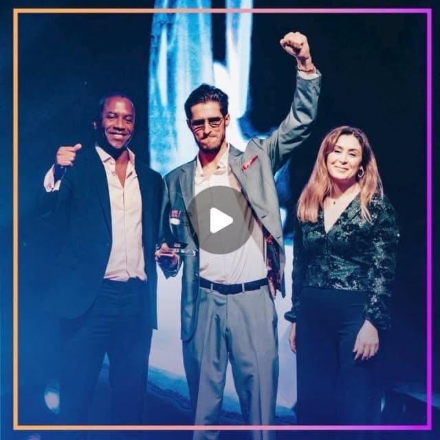 Matthias Mende raising a fist on stage holding the MEBA award